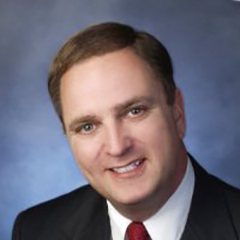 A man in suit and tie smiling for the camera.